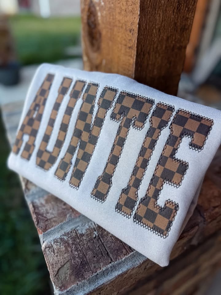 Brown checkered AUNTIE appliqué on a Gildan crewneck, angled view